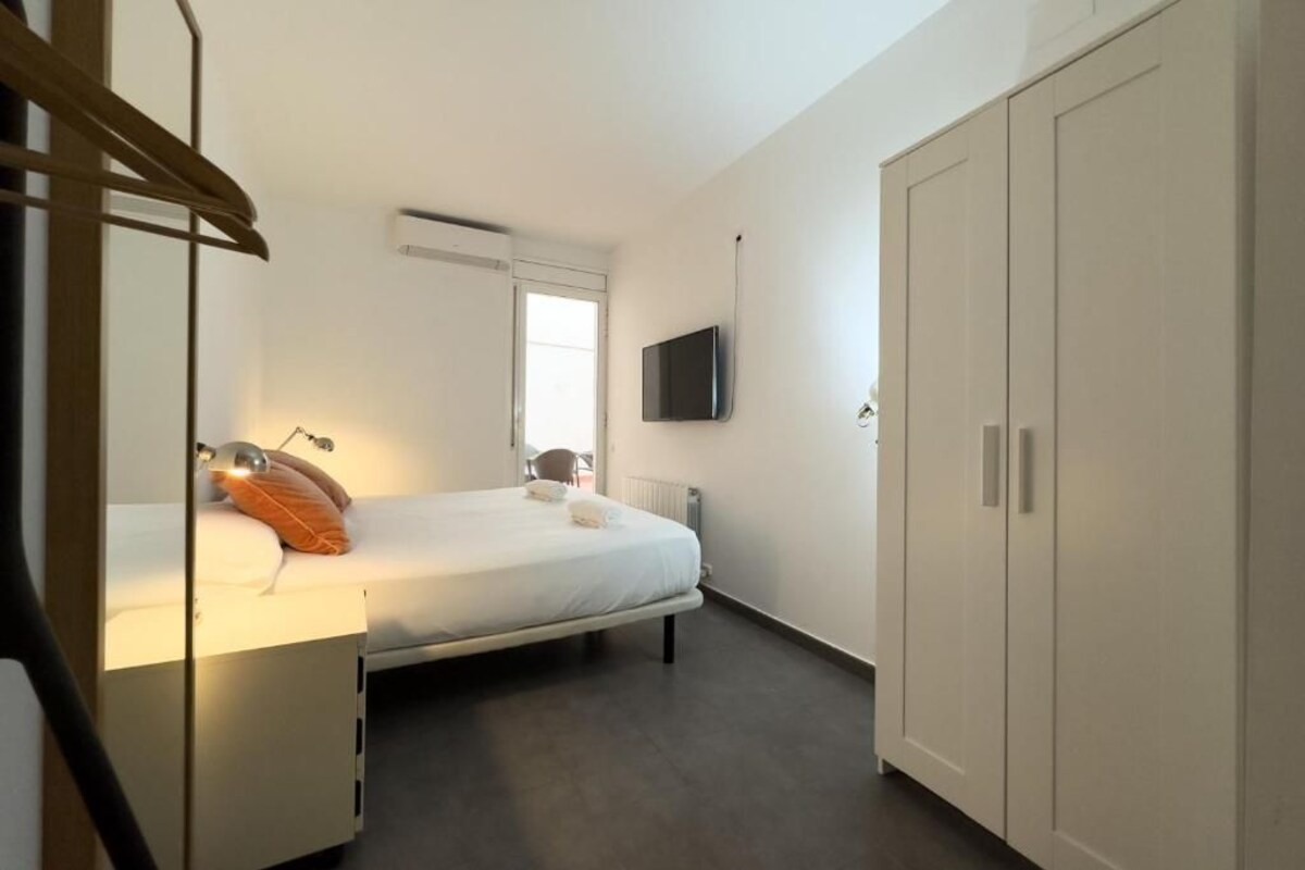 Un dormitorio con cama, televisor en la pared y armario.