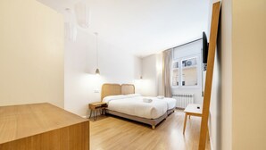 Moderni hotellihuone, jossa on suuri sänky, yöpöydät, työpöytä ja suuri ikkuna, josta on näkymä.