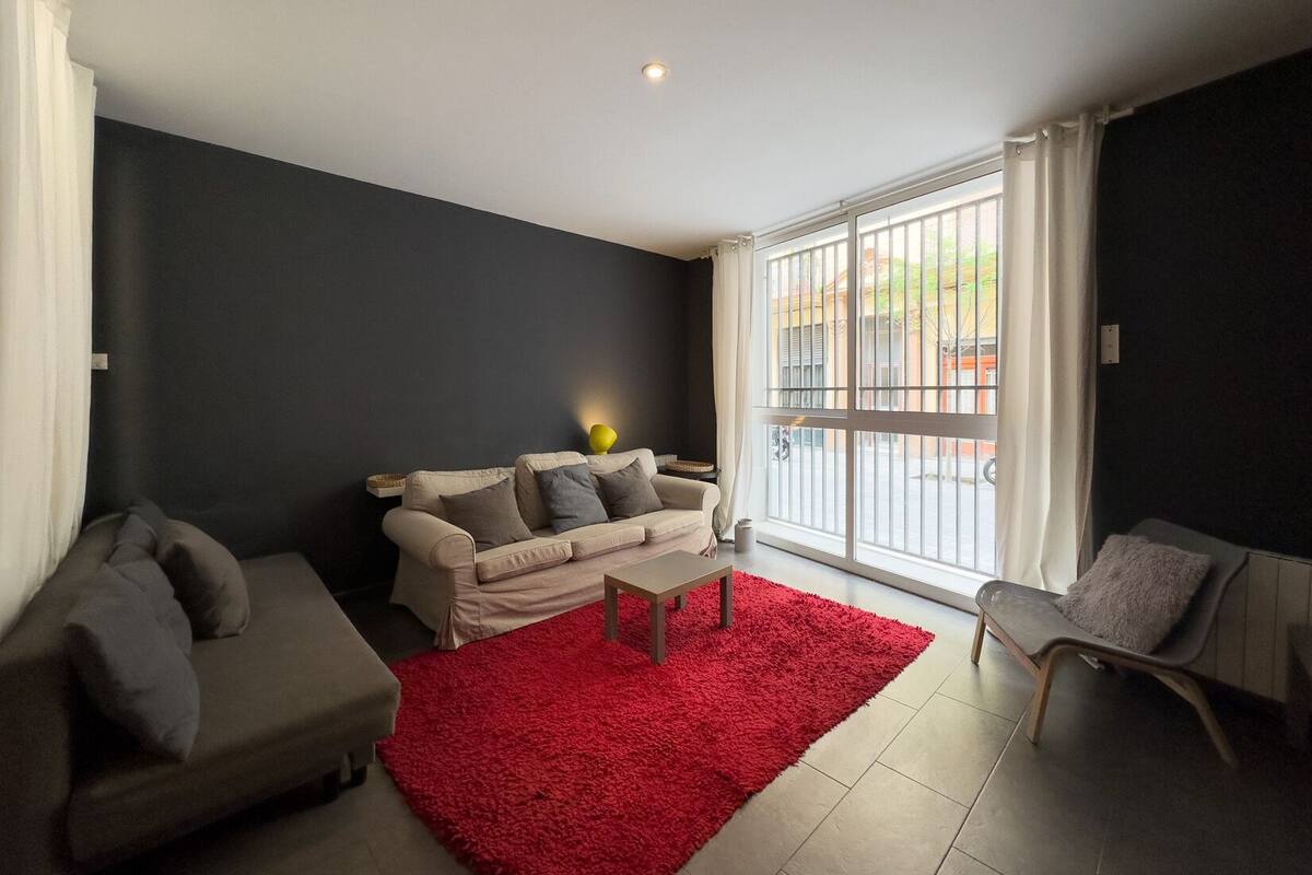 A living room with a sofa, a chair, a coffee table, and a red rug.