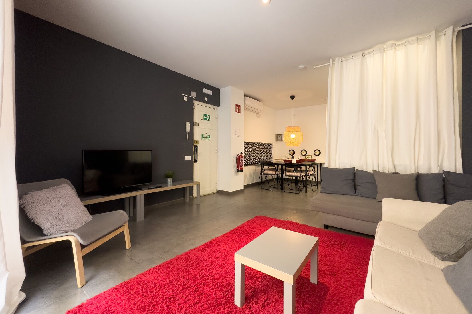 A modern living room with a TV, sofa, and red carpet.