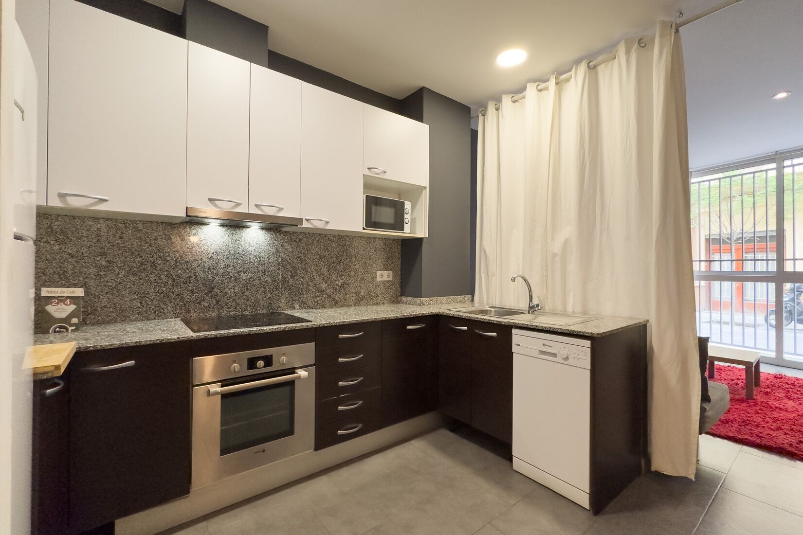 A compact kitchen with dark cabinets, a microwave, a stove, and a dishwasher.