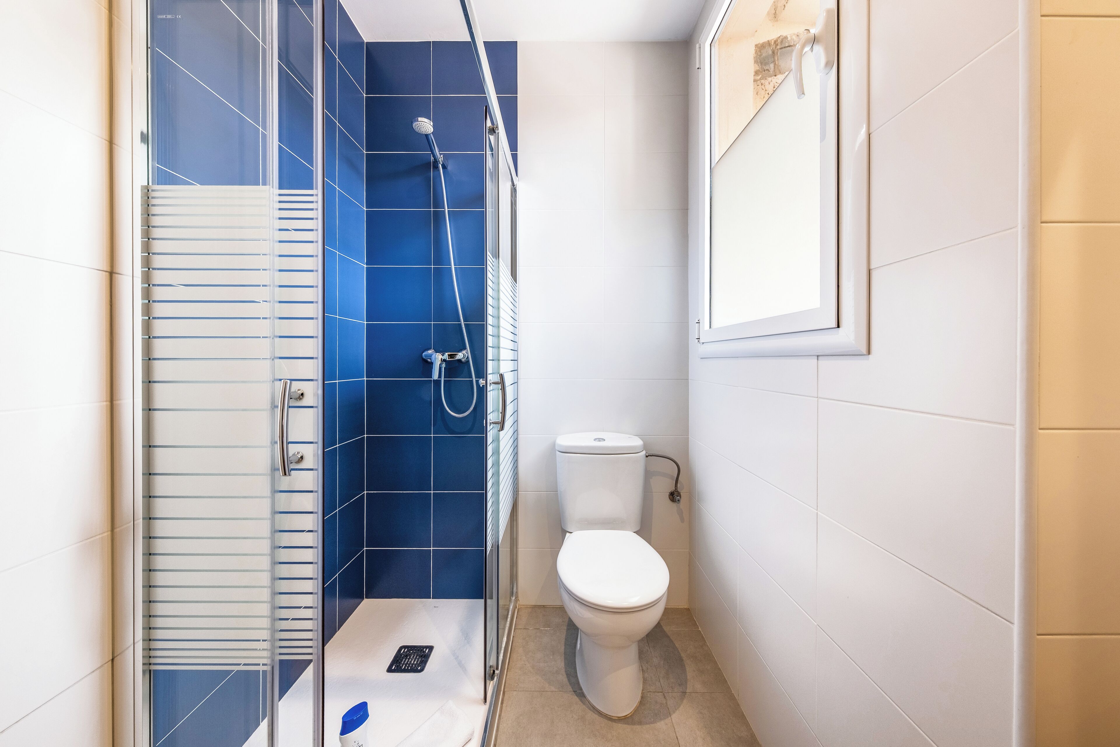 A small bathroom with a shower, toilet, and a glass door.