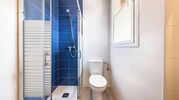 A small bathroom with a shower, toilet, and a glass door.