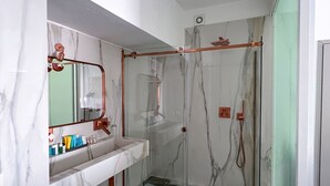 Een badkamer met een marmeren wastafelmeubel, een douchecabine van glas en een vloer met een patroon.