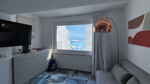 Een moderne kamer met een groot raam, een flatscreen televisie, een bank en een bijzondere vloer met een patroon.