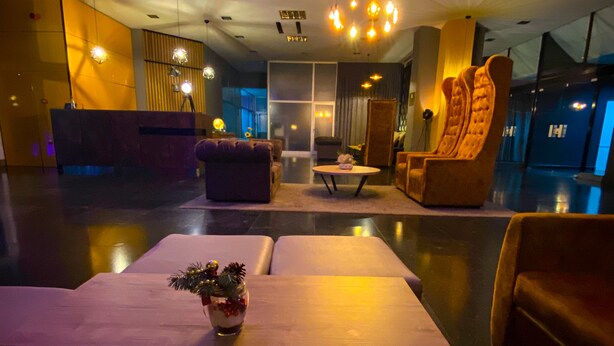 A modern hotel lobby with a reception desk, seating area, and a large chandelier. - Business Hotel Prijedor (Prijedor)
