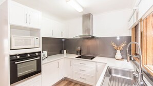 A modern kitchen with white cabinets, a stainless steel sink, and a microwave.