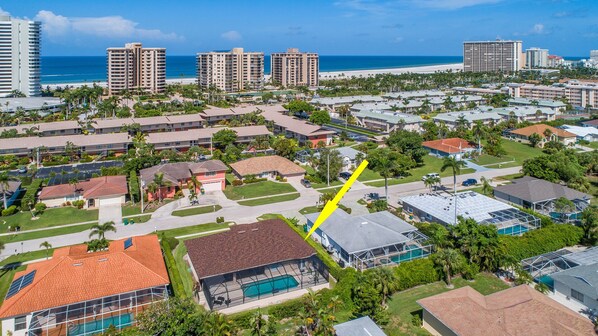 A residential area with multiple buildings, a swimming pool, and a view of the beach.