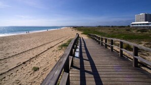A wooden boardwalk leading to a beach with a building in the background. - Alvor Bay Dream by Interhome (Alvor)