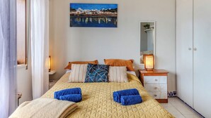 A bedroom with a bed, pillows, a nightstand, a lamp, a painting, and a wardrobe. - Alvor Bay Dream by Interhome (Alvor)