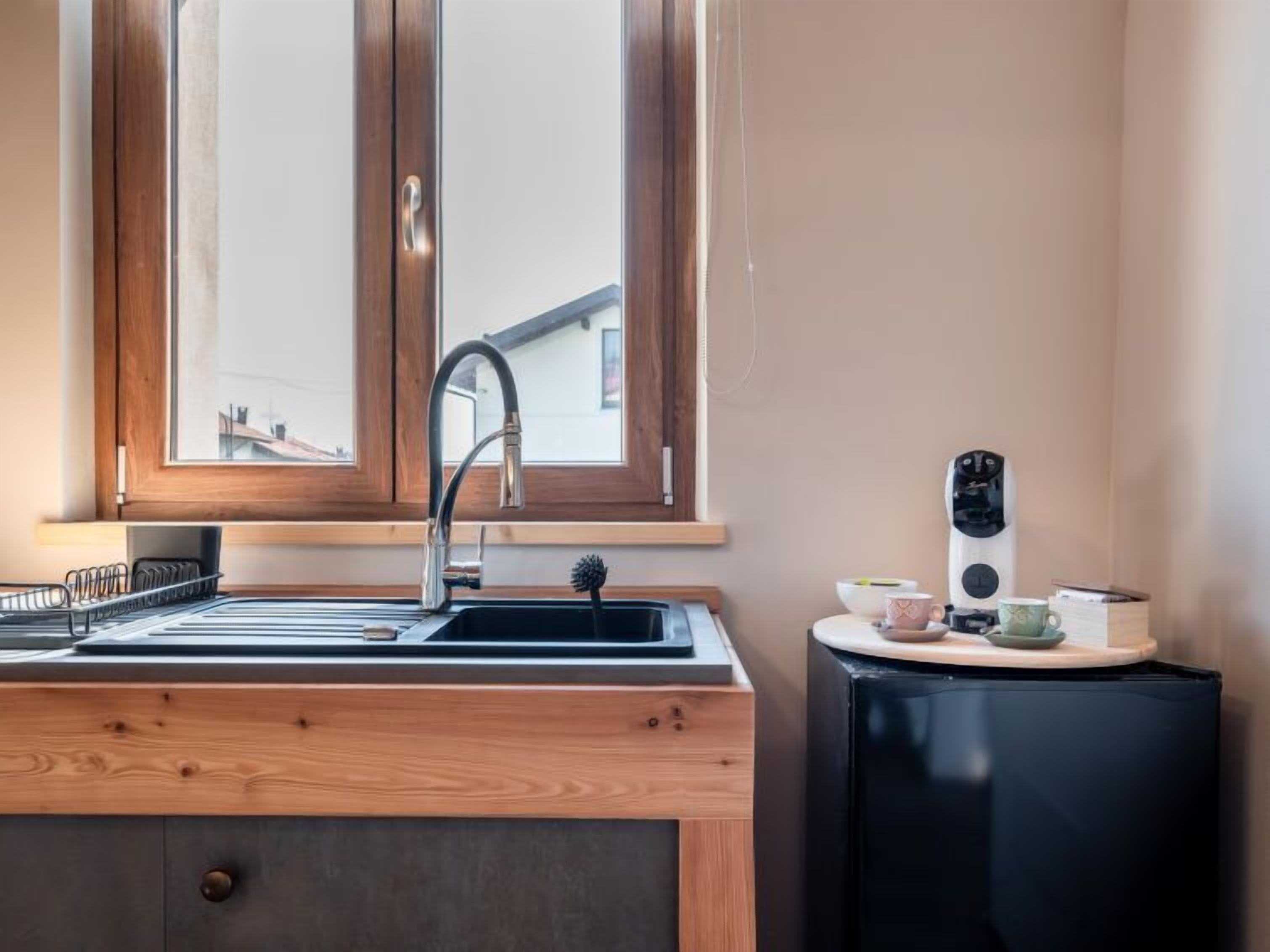Una cocina con encimera de madera, pileta de acero inoxidable, ventana sobre la pileta y cafetera en la encimera.
