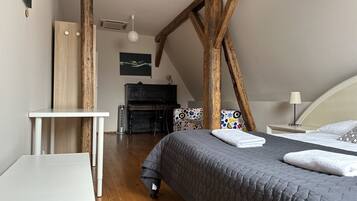 A bedroom with a bed, a desk, a chair, a piano, and a ceiling fan.