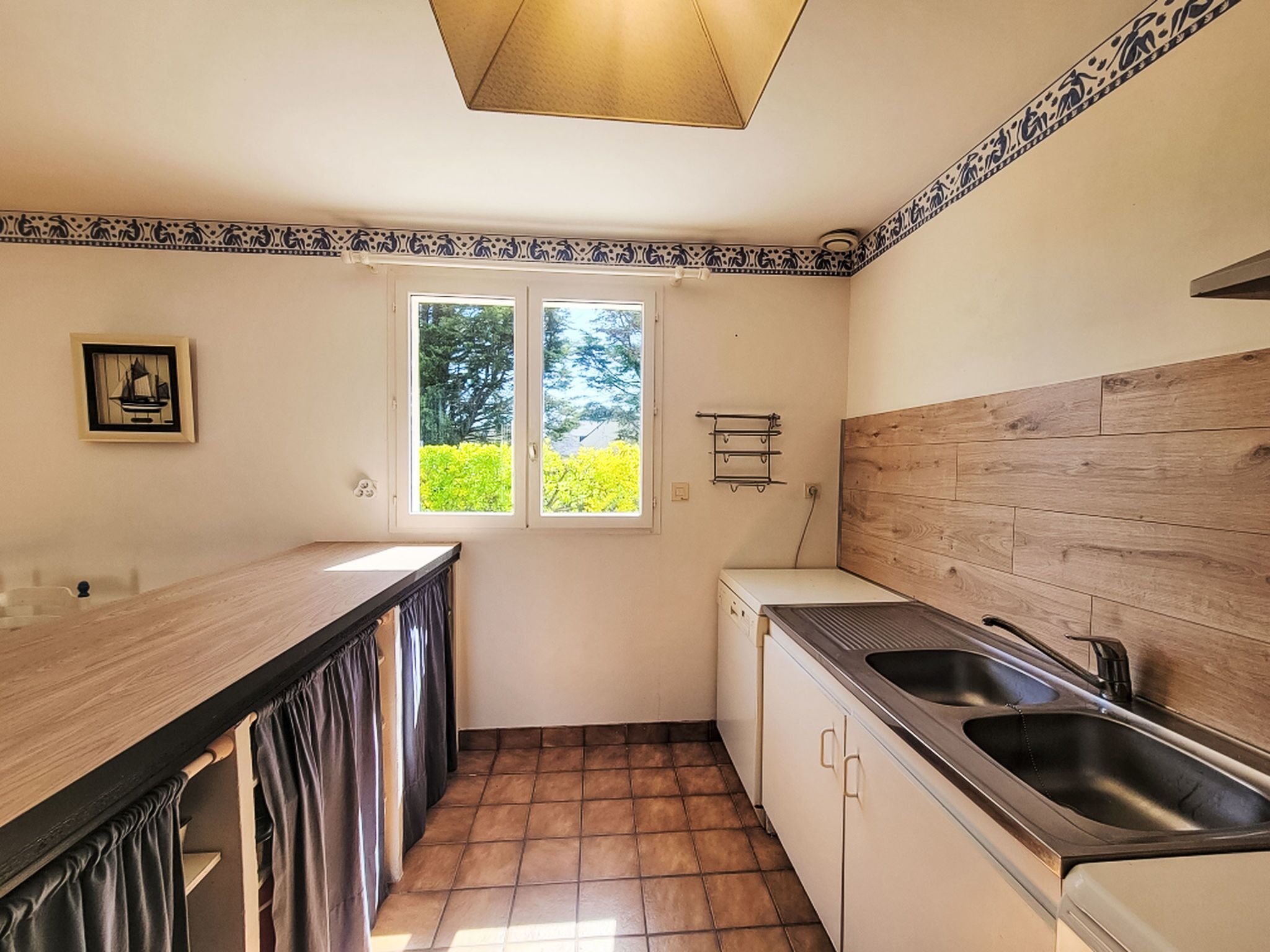 Eine kleine Küche mit Fenster, Spüle und kleinem Kühlschrank.