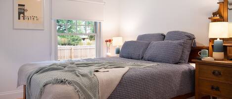 A bedroom with a bed, bedside table, lamp, and a framed picture on the wall.
