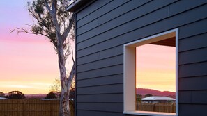 A house with a window opening to a sunset view, a wooden fence, and a tree. - Reader's Rest - dog friendly accommodation in Clunes! (Clunes)