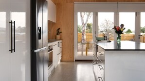 Una cucina moderna con frigorifero in acciaio inox, mobili bianchi e un'ampia finestra vista giardino.