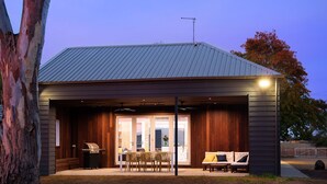 Un'area esterna coperta con barbecue, tavolo e sedie da pranzo.