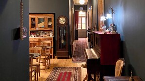 A hallway with a wooden bench, a red rug, a clock, and a wooden cabinet. - VASILIKON Hotel 1888 the past is present (Kalamata)