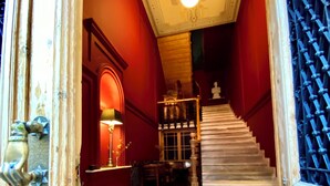 A grand staircase with a red carpet leading to a room with ornate decor and a chandelier. - VASILIKON Hotel 1888 the past is present (Kalamata)