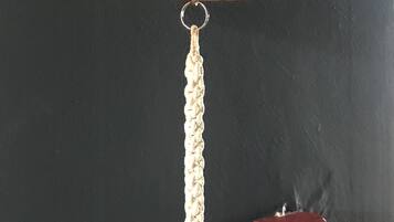 A brass bell with a white tassel hanging from a black wall.