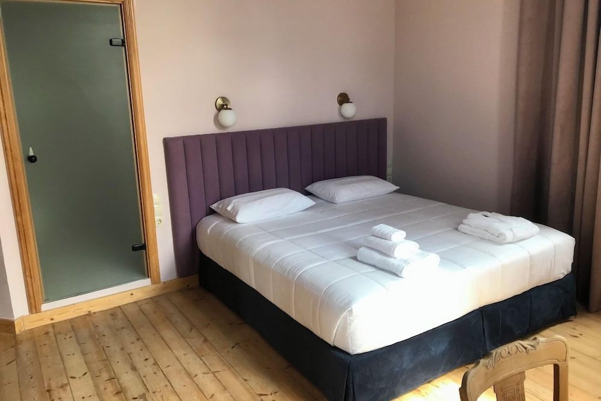 Habitación de hotel con cama, piso de madera, puerta y aplique.