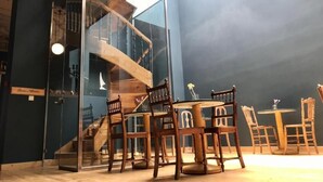 A room with a wooden staircase, a round table with chairs, and a glass partition. - VASILIKON Hotel 1888 the past is present (Kalamata)