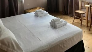 A hotel room with a bed, two windows with curtains, a chair, and a small table. - VASILIKON Hotel 1888 the past is present (Kalamata)