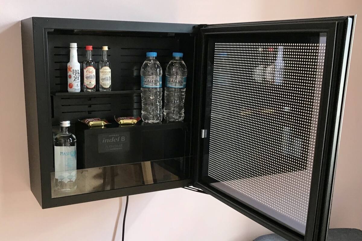 A black cabinet with a glass door, containing bottles and a box labeled "indel B".