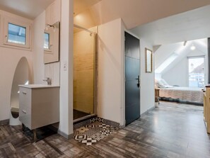 Ein modernes Schlafzimmer mit Bett, begehbarem Kleiderschrank und einem Badezimmer mit Dusche.