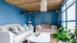 Una habitación acogedora con pared azul, suelo de madera, una mesa de centro blanca y dos sofás.