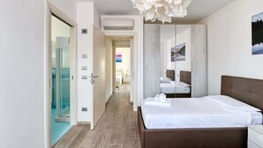 Moderni hotellihuone, jossa on suuri sänky, peili ja ainutlaatuinen kattovalaisin.