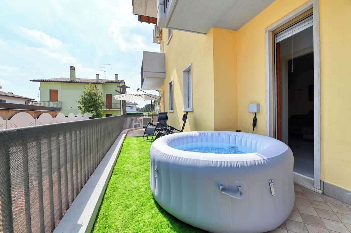 An outdoor area with a round inflatable pool, a small lawn, and a patio with outdoor furniture.