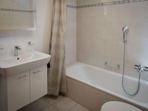 Une salle de bain avec un lavabo blanc, une baignoire et une douche.