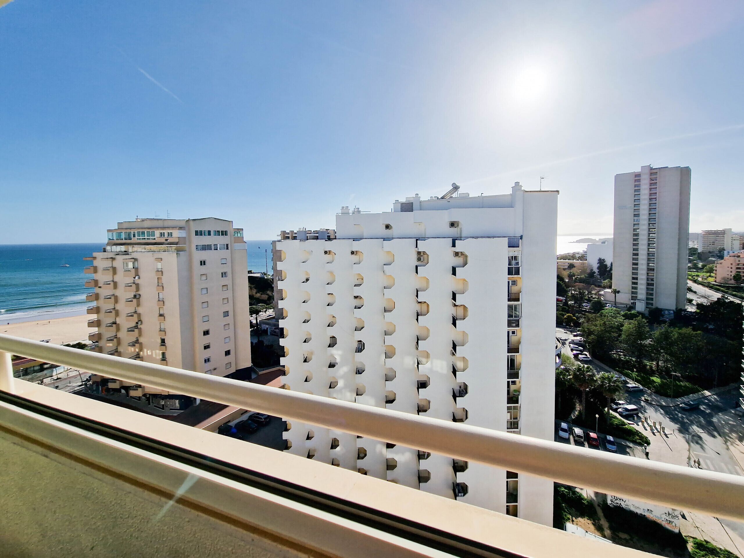 Een hoog appartementencomplex met balkons met uitzicht op een strand en de oceaan.