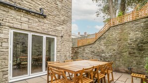 A stone building with a wooden table and chairs, a glass door, and a stone staircase. - Belle Vue (Hereford)