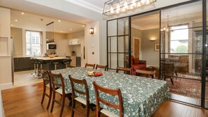 A dining area with a table set for four, wooden chairs, and a green floral tablecloth. - Belle Vue (Hereford)