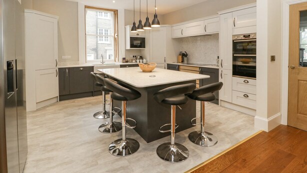 A modern kitchen with a central island, bar stools, pendant lighting, and built-in appliances. - Belle Vue (Hereford)