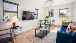 Ein modernes Wohnzimmer mit Sofa, Couchtisch, Fernseher und Essbereich.