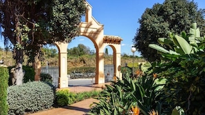 Un jardín con una pérgola, un sendero y diversas plantas.