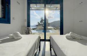 A room with two beds, a view of a pool, and a mountain in the background. - Villa Saphora in Lefkada (Lefkada)