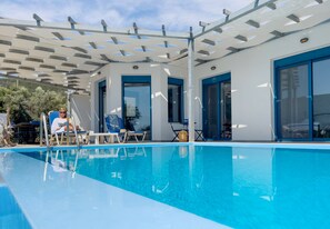 A swimming pool with clear blue water, surrounded by lounge chairs and a pergola structure. - Villa Saphora in Lefkada (Lefkada)