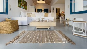 A modern living room with a white sofa, a coffee table, and a woven rug. - Villa Saphora in Lefkada (Lefkada)