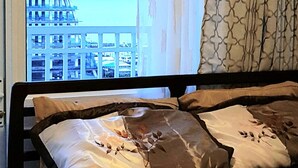 Una cama con ropa de cama floral y vista a un edificio a través de una ventana.
