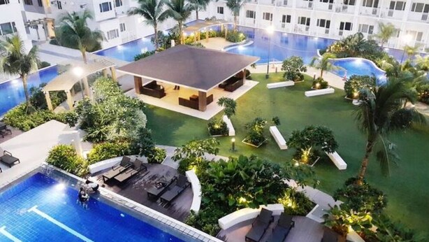 Un hotel con varias piscinas, zonas de estar al aire libre y abundante vegetación.