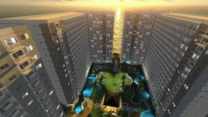 Un edificio alto con varios pisos, una piscina en la azotea y un área ajardinada circundante.