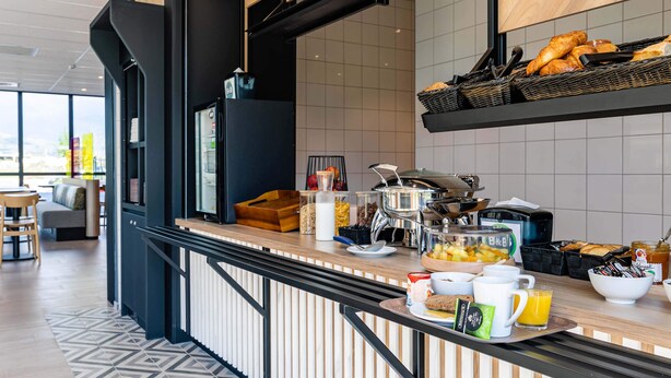 Een moderne ontbijtbar met diverse etenswaren, een koffieapparaat en een zithoek met uitzicht.