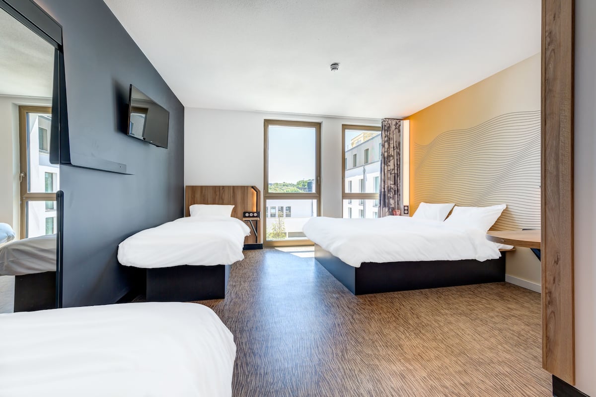 Ein Hotelzimmer mit zwei Betten, einem großen Spiegel, einem Fernseher und Blick ins Freie.