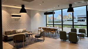 Een modern interieur met een bank, stoelen, een tafel en grote ramen met uitzicht.
