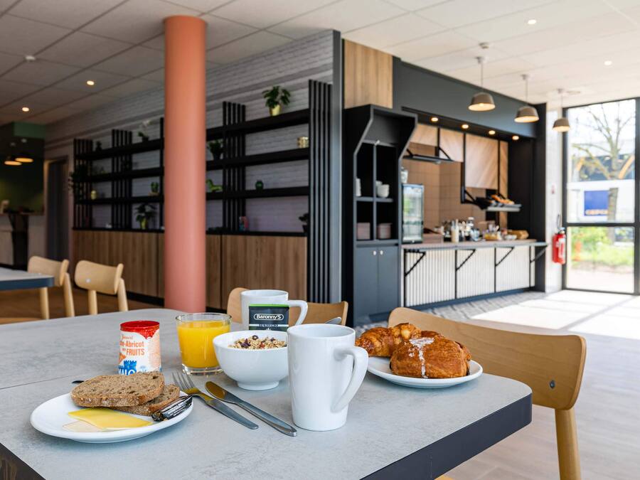 Ein Frühstückstisch mit Speisen und Blick in den Küchenbereich.