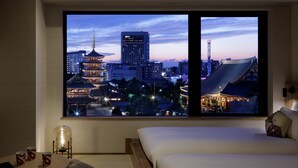 A hotel room with a large window offering a view of a cityscape at dusk, including traditional and modern buildings. - OMO3 Asakusa by Hoshino Resorts (Tokyo)